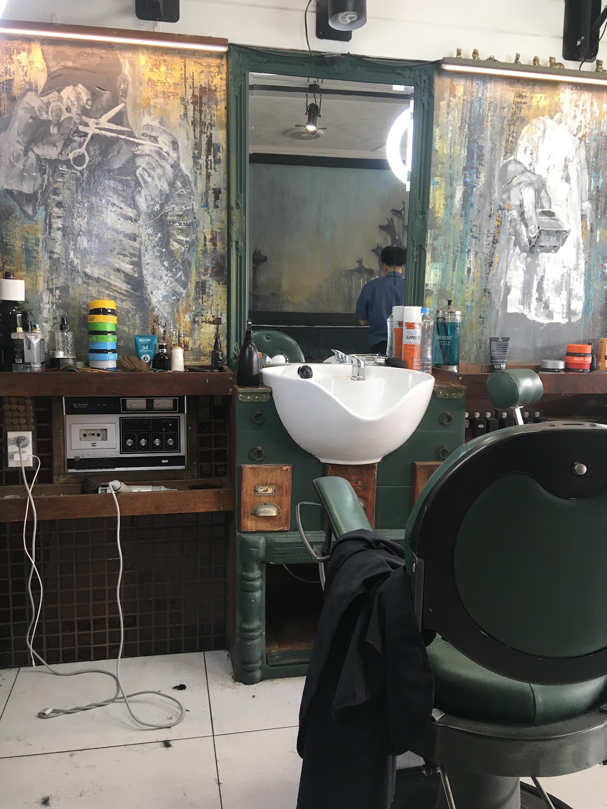 Green washbasin station beneath murals and a vintage cassette deck