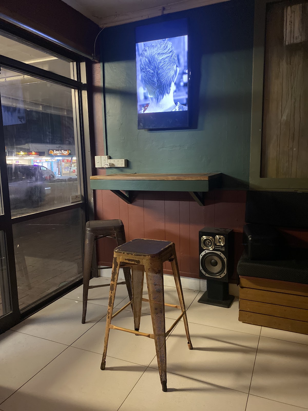 Waiting corner with stools and a screen showing cuts